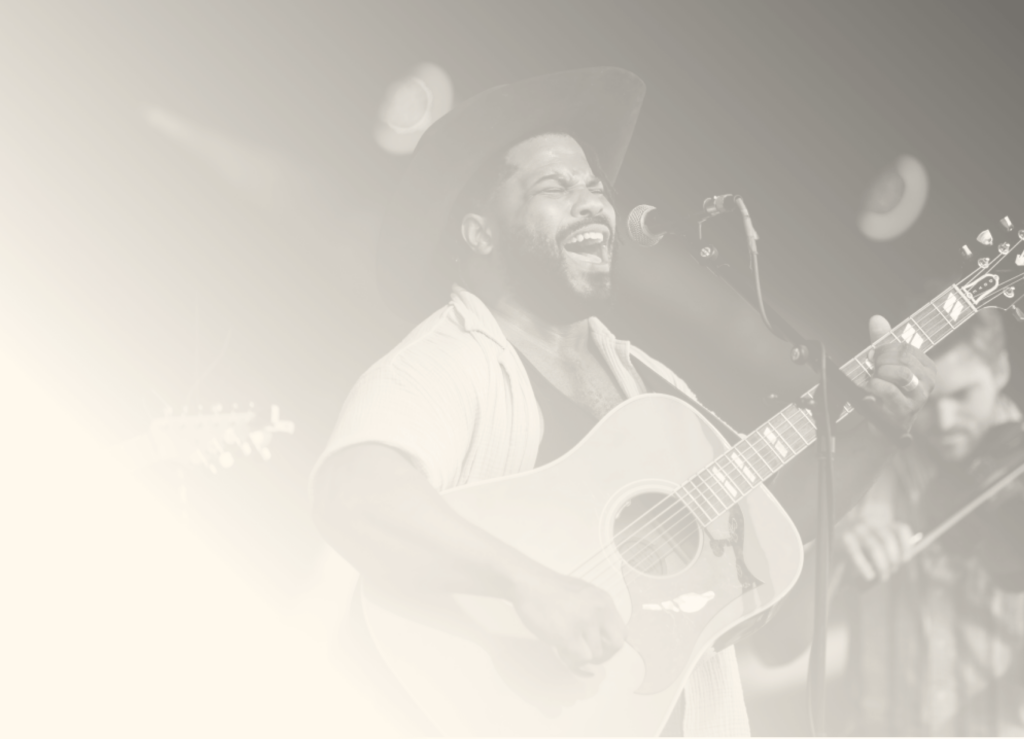 A black and white image of a performer singing and playing guitar