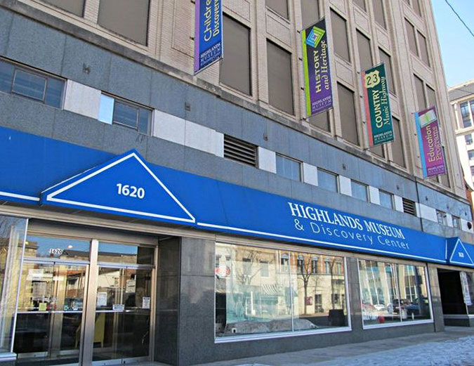 The exterior of the museum, with blue awnings on a city street.