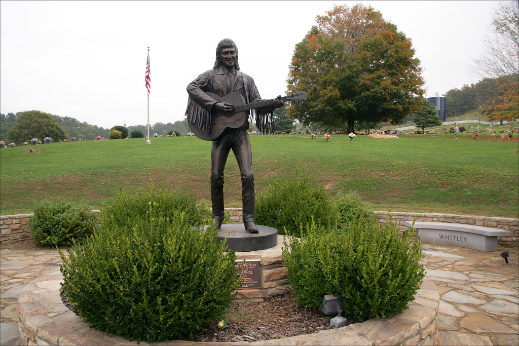 A metal statue of a man in a fringed jacket holding a guitar