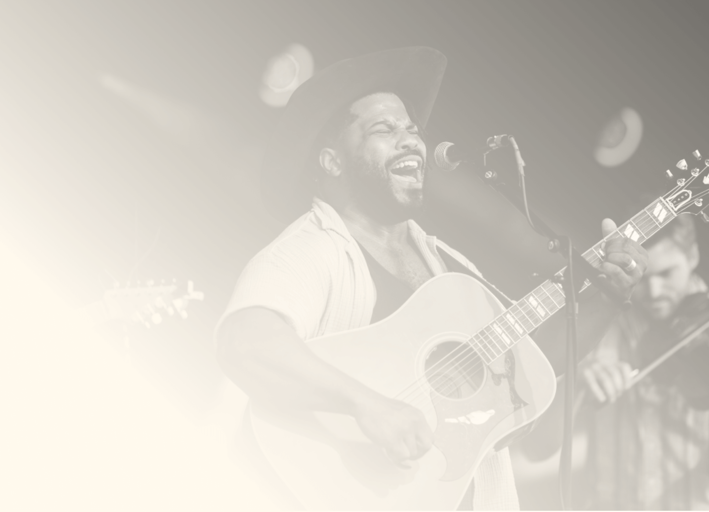 A black and white image of a performer singing and playing guitar