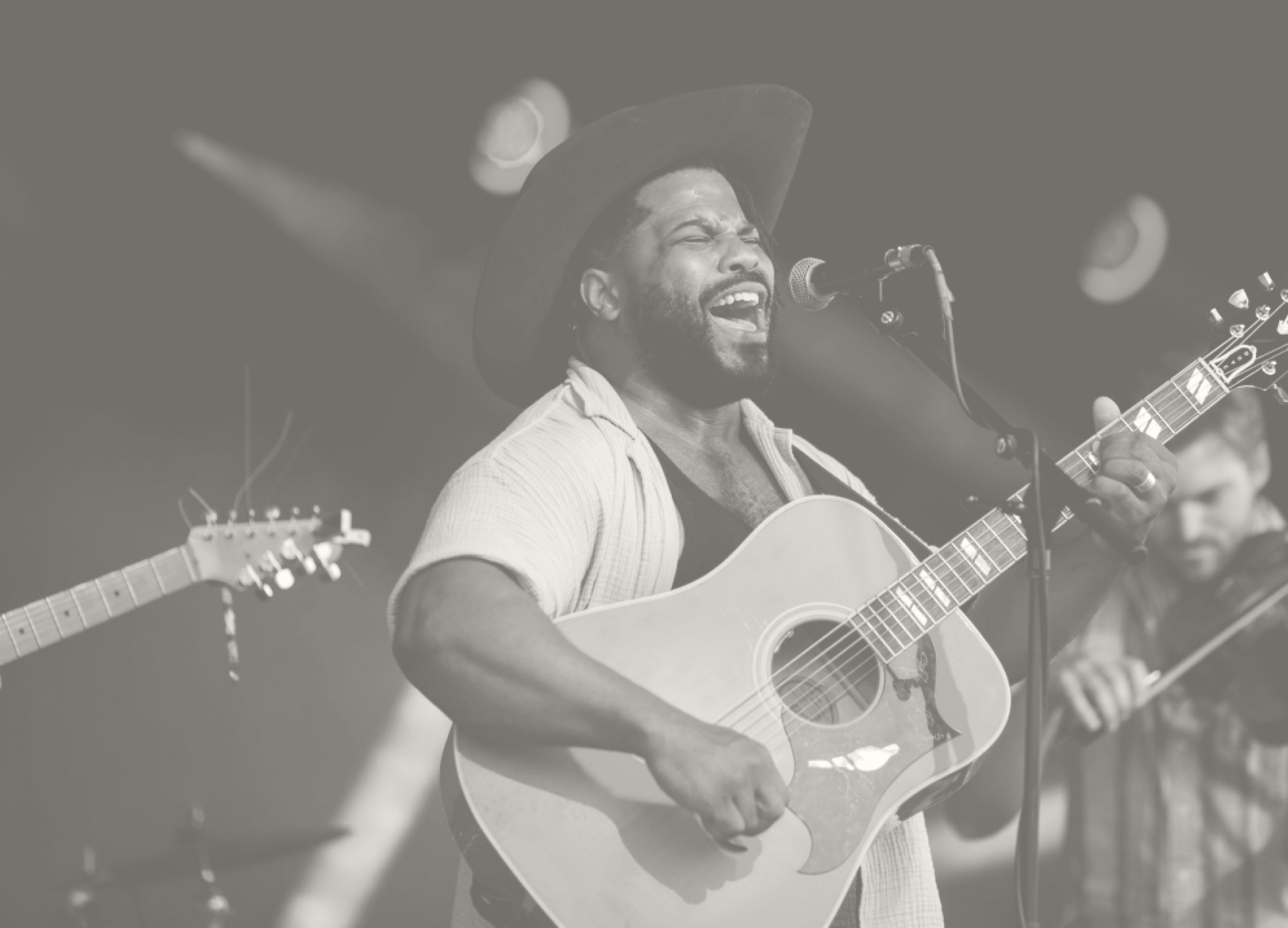 A black and white photo of a musician who sings and performs on stage with an acoustic guitar.